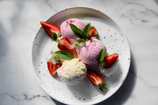 A refreshing plate of strawberry and vanilla ice cream with fresh mint and sliced strawberries.